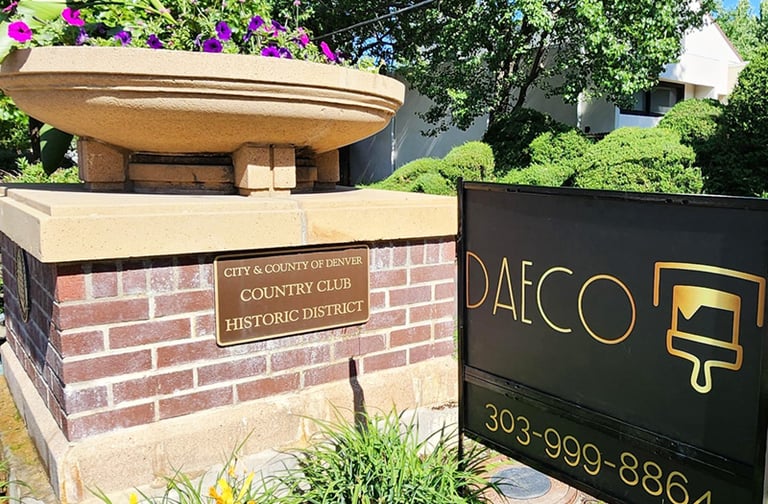 Daeco Painting business sign next to the Denver Country Club Historic District plaque on a brick pil