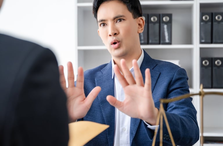 a man in a suit and tie is sitting at a desk hands up