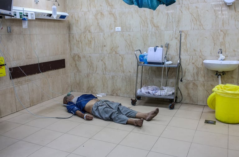 A patient lying on a hospital floor getting oxygen and IV to medical facility unavailable mass loss 