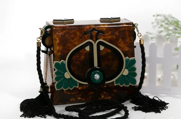 a small tortoid box - top handbag with a green and white flower