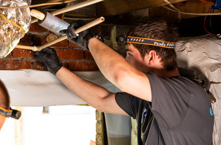 Caleb Smith piecing PVC Pipe in a crawlspace