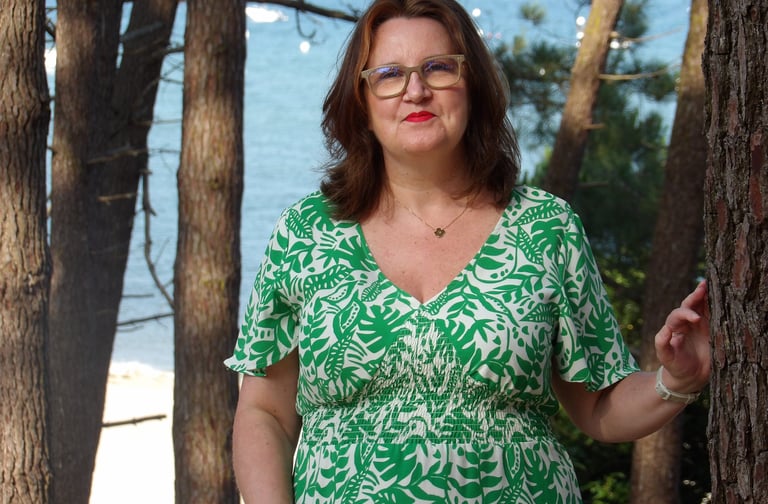 Portrait de la sophrologue en extérieur, devant un paysage de mer et de pins, illustrant le contact.