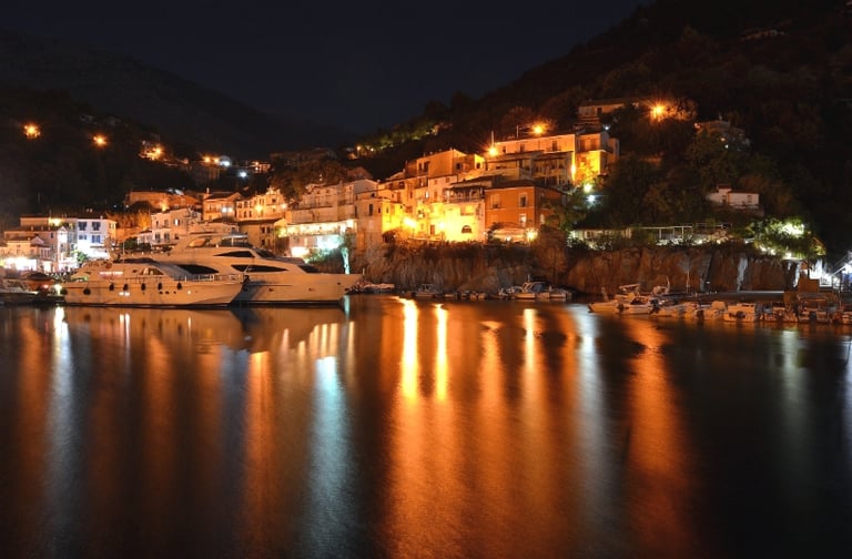 Vista notturna di yacht di lusso nel porto di maratea, con le luci che si riflettono in acqua