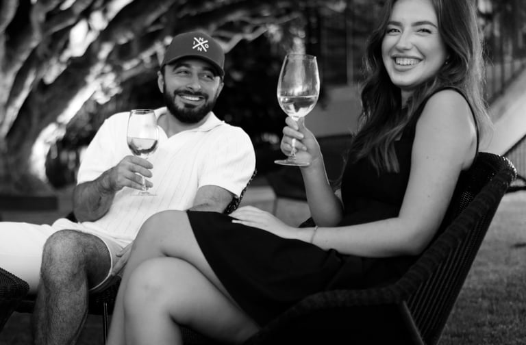 Couple enjoying wine together on outdoor terrace in Madeira, relaxing lifestyle and romantic vibe beneath leafy trees.