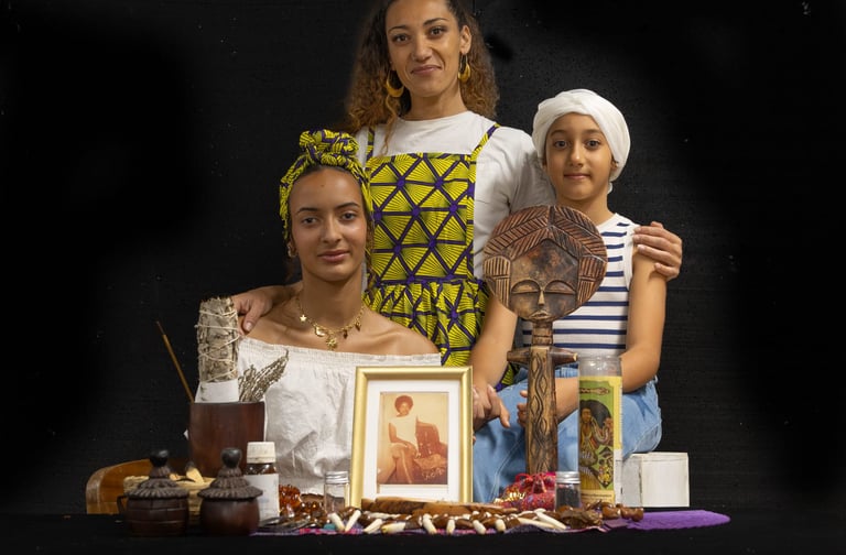 Three women posing behind a spiritual altar with an African wood carving and sage.