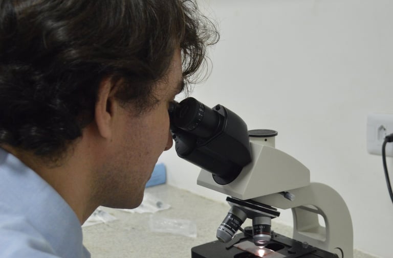 Citologista clínico analisando amostra em microscópio.