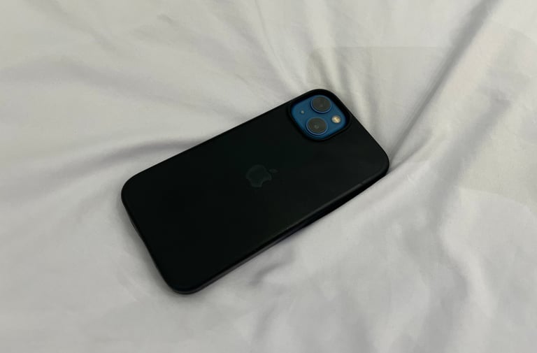 iPhone 13 with black case and a phone wallpaper of a girl 