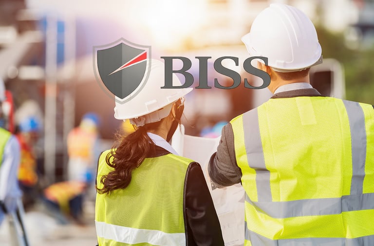 Two construction engineers wearing hard hats and safety vests at a busy building site for BISS safety services.