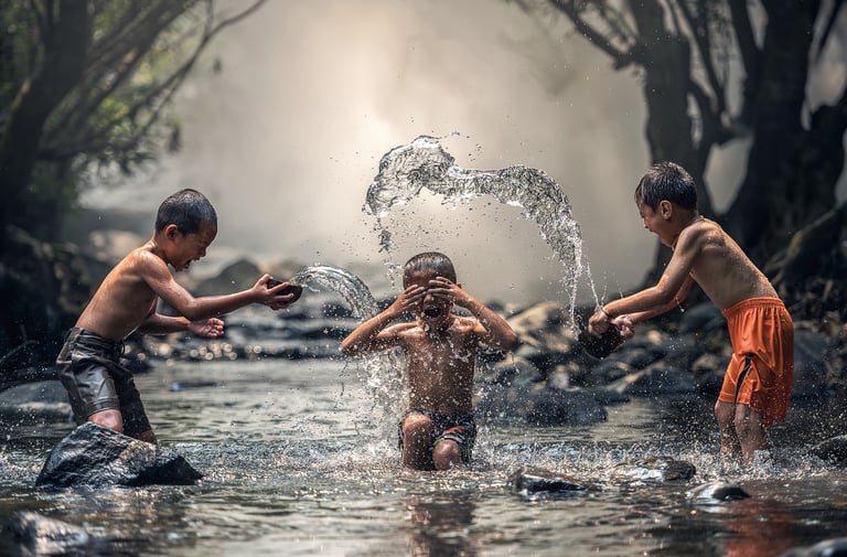 Tres niños jugando en el agua, simbolizando alegría y bienestar