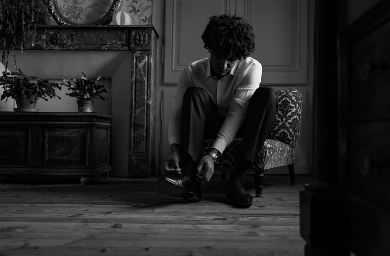 Un homme en chemise blanche assis laçant ses chaussures