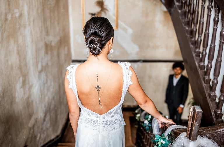 Une femme en robe de mariée dans les escaliers regardant son futur mari