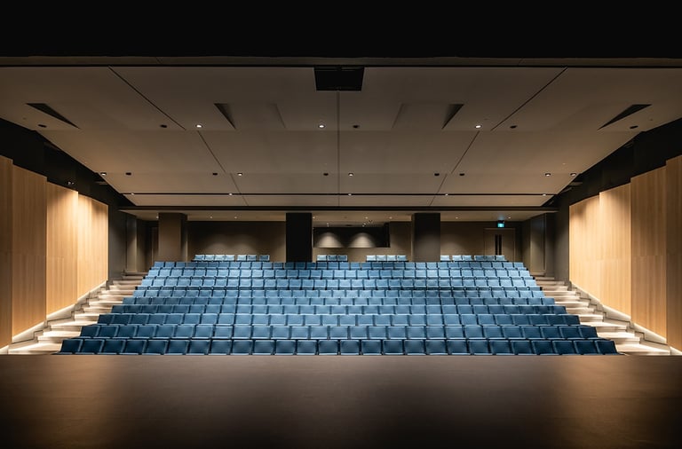 a large auditorium with blue chairs and a stage