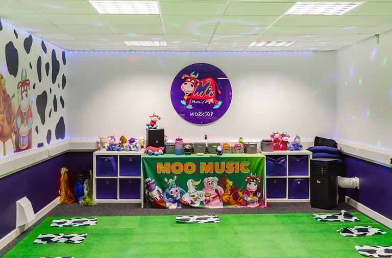A picture of the Moo room, showing the front table, logo and bright set up of the room