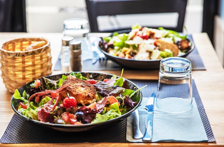 a table with a bowl of salads and a glass of water