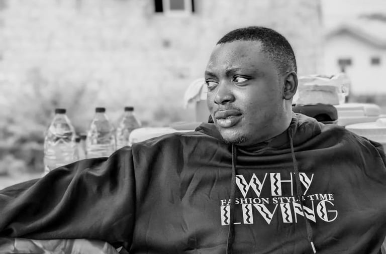 a man wearing a black jacket, siting down and look sideways