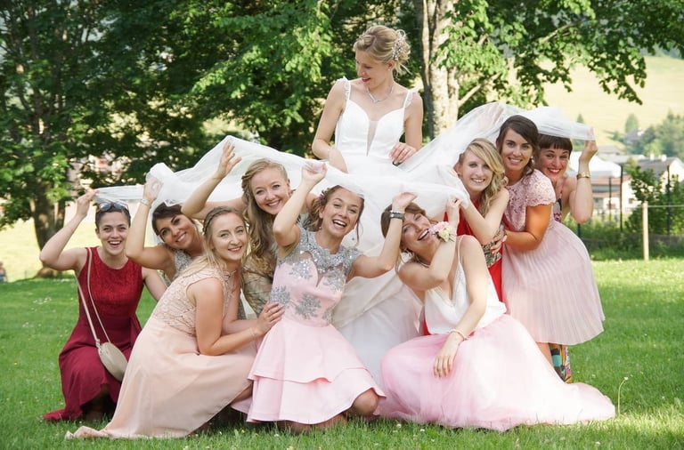 photography og a bride with best women plaing under her wedding dress, they smile and laugh.