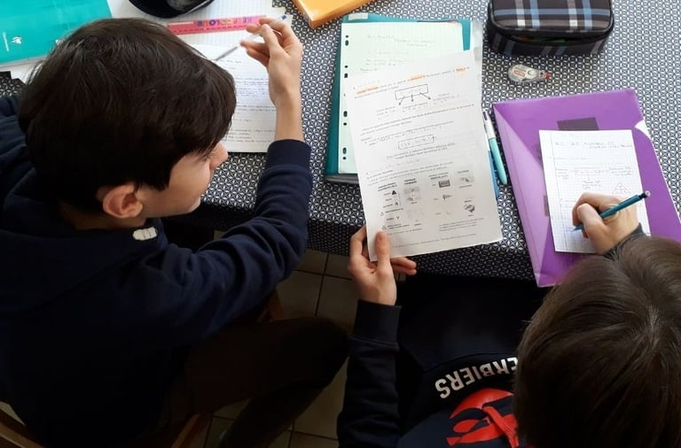 two boys sitting at a table with notebooks