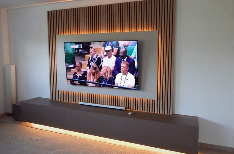 Modern living room entertainment center featuring a wall-mounted TV on a wood slat accent wall with LED backlighting.