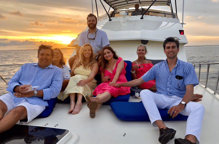 A group of friends enjoys a luxury sunset yacht cruise with drinks on the deck.