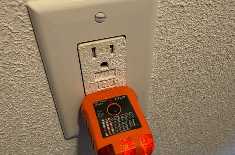 An orange GFCI outlet tester plugged into a white wall socket to check for proper electrical wiring.