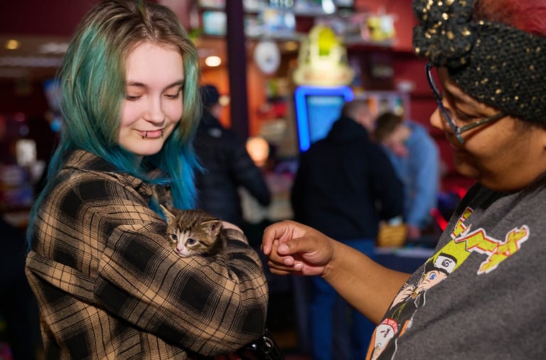 a woman with blue hair holding a kitten on her arm