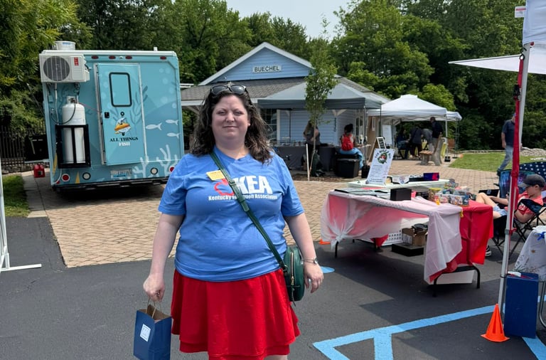 Woman in KEA tshirt standing in front of booths at the public library cultural pass kickoff