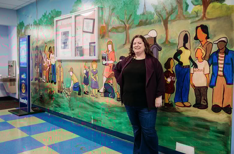 Woman in purple sweater standing in front of painted mural