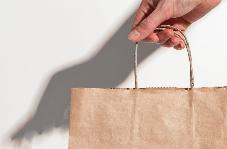 une main qui tend un sac en papier kraft
