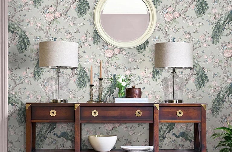 Elegant peacock floral wallpaper behind a dark wood console table with table lamps and a round mirror.