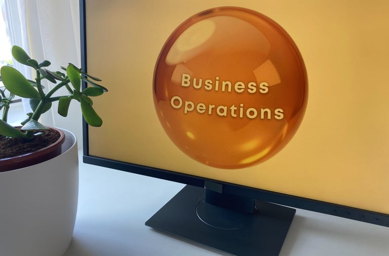 Business Operations logo on PC monitor plant and curtain