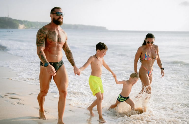 Family enjoying playful moments together near the ocean during a candid family photography session at Dreamland Beach Bali.
