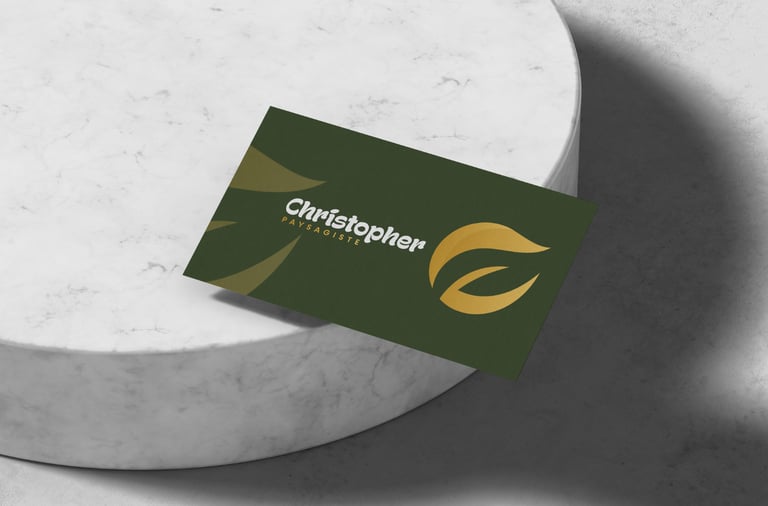 Carte de visite verte pour paysagiste avec logo en feuille d'or sur un piédestal en marbre blanc.