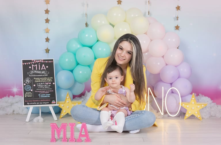 a woman holding a baby in front of a rainbow colored backdrop