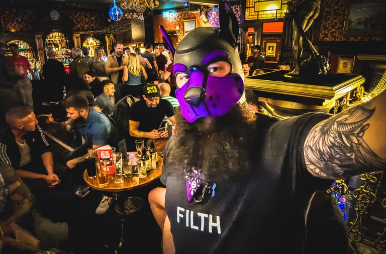 Man in a pup mask, standing in a pub taking a selfie.
