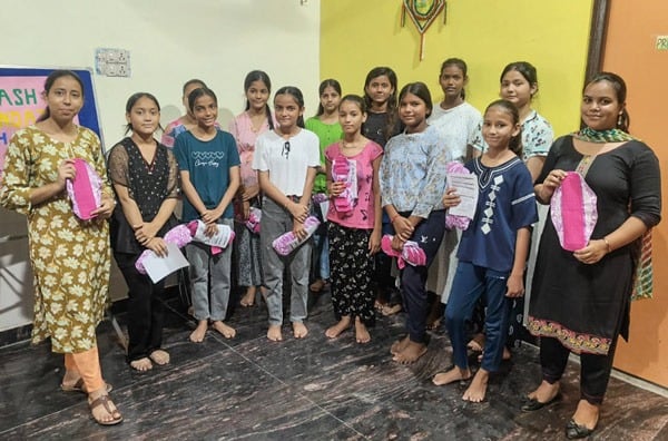 Small class of schoolgirls holding up a Hanaru reusable sanitary napkin