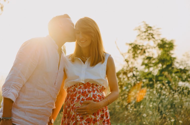 una donna incinta e un uomo che si baciano al tramonto