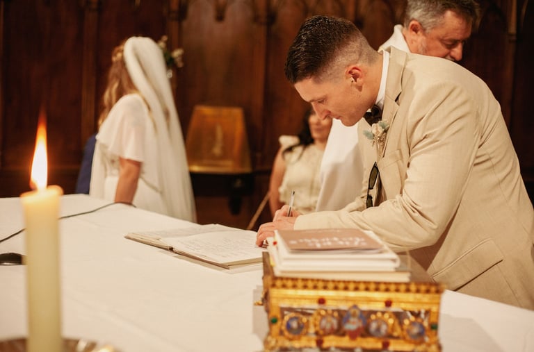 photo aux ton chalereux d'un témoin signant le registre lors du mariage
