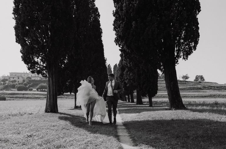 a bride and groom walking down a path in a field