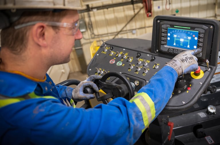 A heavy equipment technician is inspecting the hydraulic settings on a Bomag paving machine's digital dashboard 
