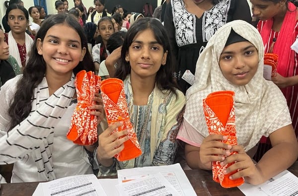3 Schoolgirls holding up a Hanaru reusable sanitary napkin