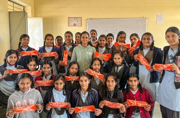 Class of schoolgirls holding up a Hanaru reusable sanitary napkin