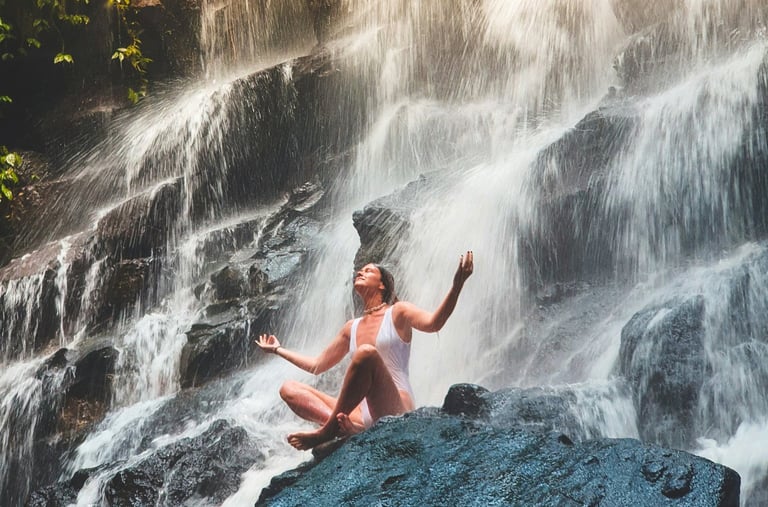 Brava Braun doing yoga on a rock in front of a waterfall