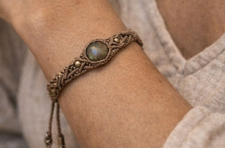 Pulsera boho de macramé hecha a mano con una piedra de labradorita en la muñeca de una mujer.