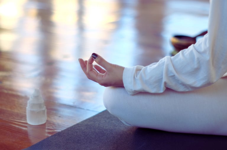 a close up of a woman's hand on a mudra position next to a selenite crystal grid