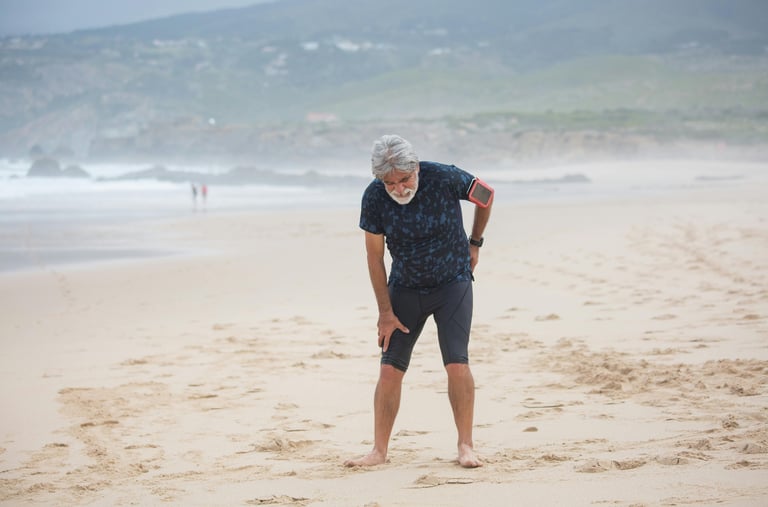 a man standing on a beach holding his back