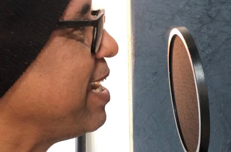 a man in a beanie hat and sunglasses is looking at a microphone