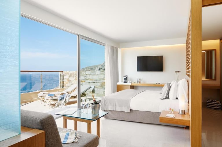 Luxury hotel room with a sea view balcony, white bedding, and modern minimalist decor.