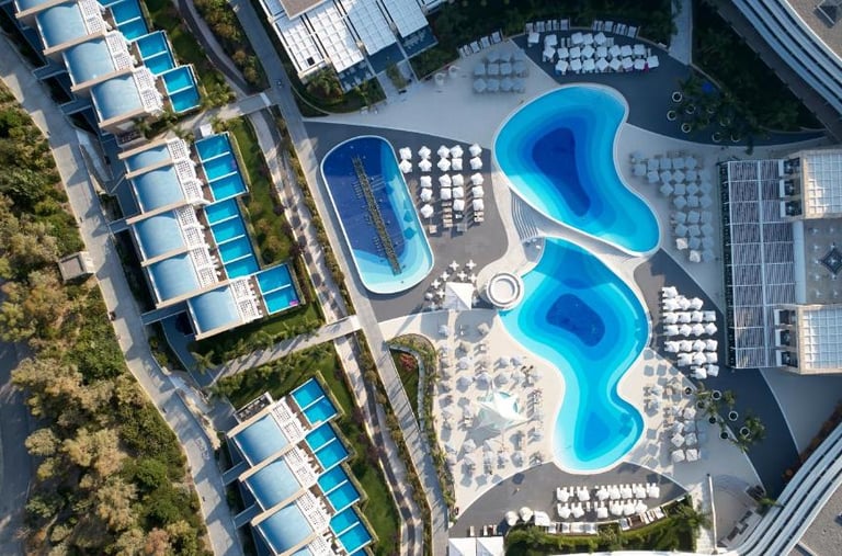 Aerial view of a luxury Princess Andriana hotel with curved swimming pools and private villa patios.