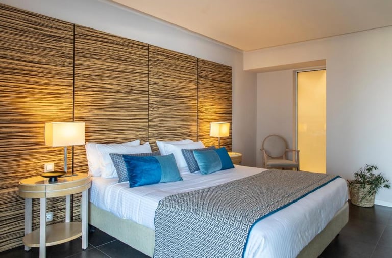 Modern luxury hotel room with blue pillows, textured wood headboard, and bedside lamps.