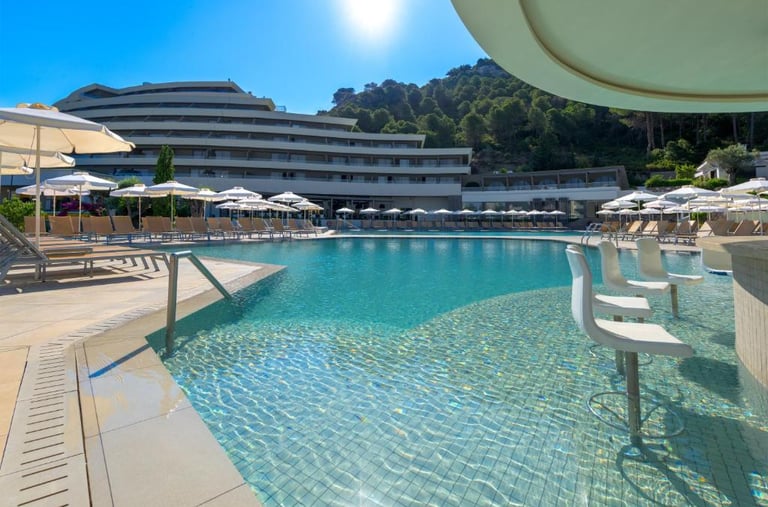 Luxury resort swimming pool with a swim-up bar, white umbrellas, and modern hotel architecture.